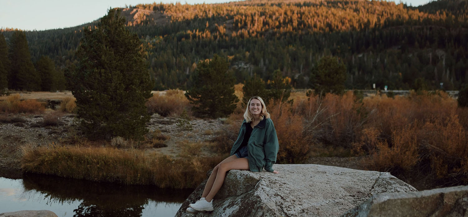 Anna in front of a mountain landscape smiling at the camera